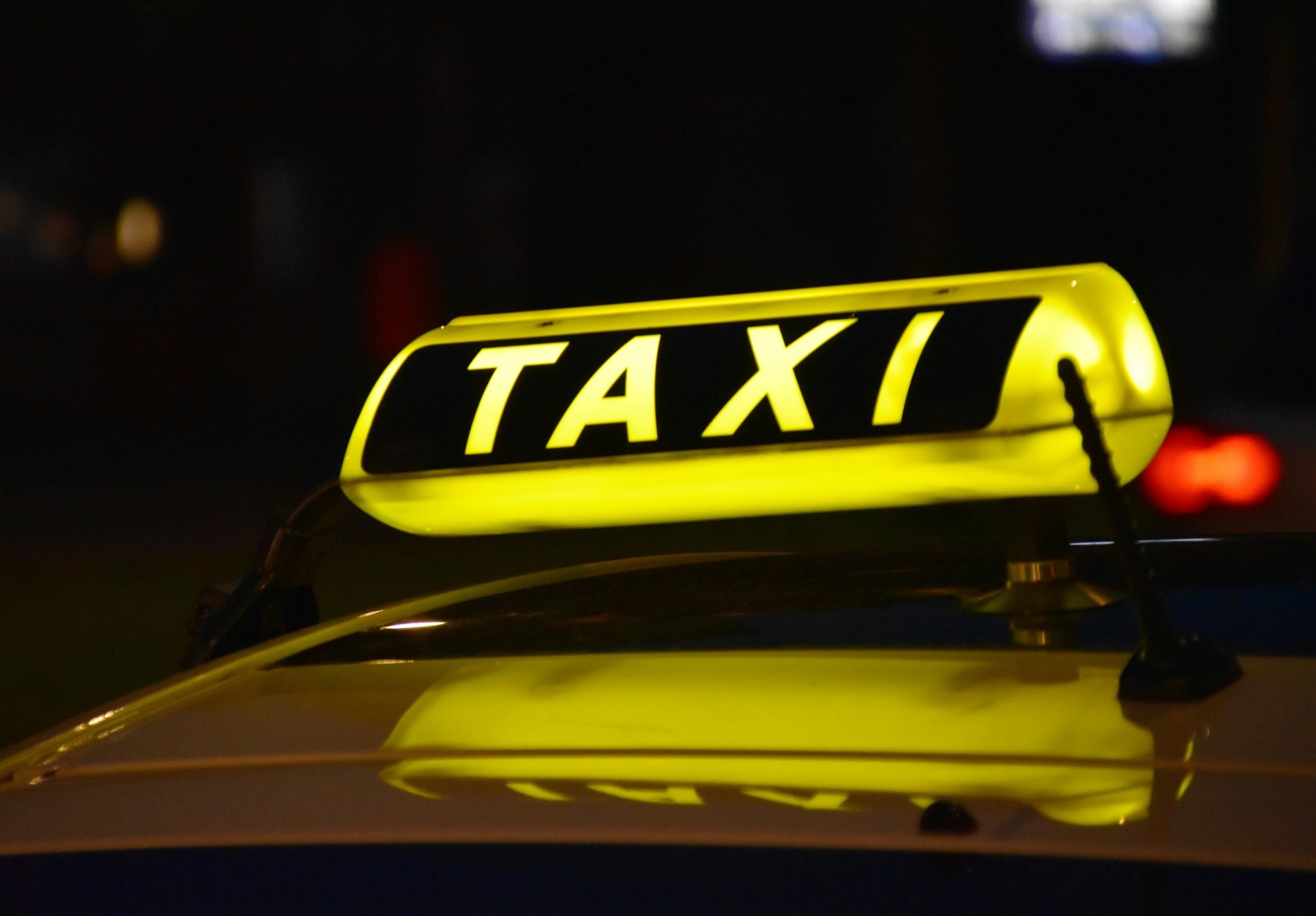 A close-up shot of a taxi sign illuminated at night.