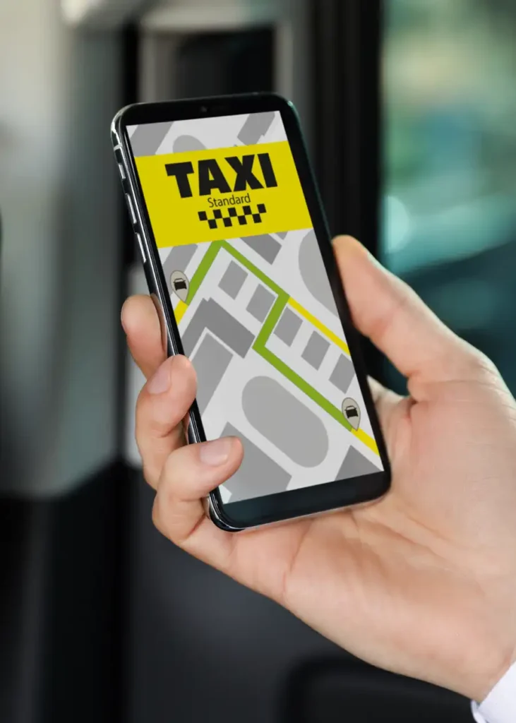 Hand holding a smartphone displaying a taxi booking app interface.